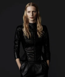 Model with long blonde hair wearing a black leather button-up top against a dark neutral studio background