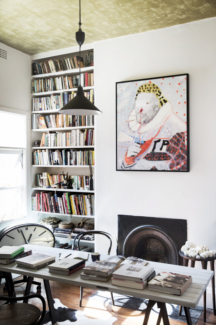Interior design showcases bookshelves filled with books, artwork above fireplace, and a dining table with books.