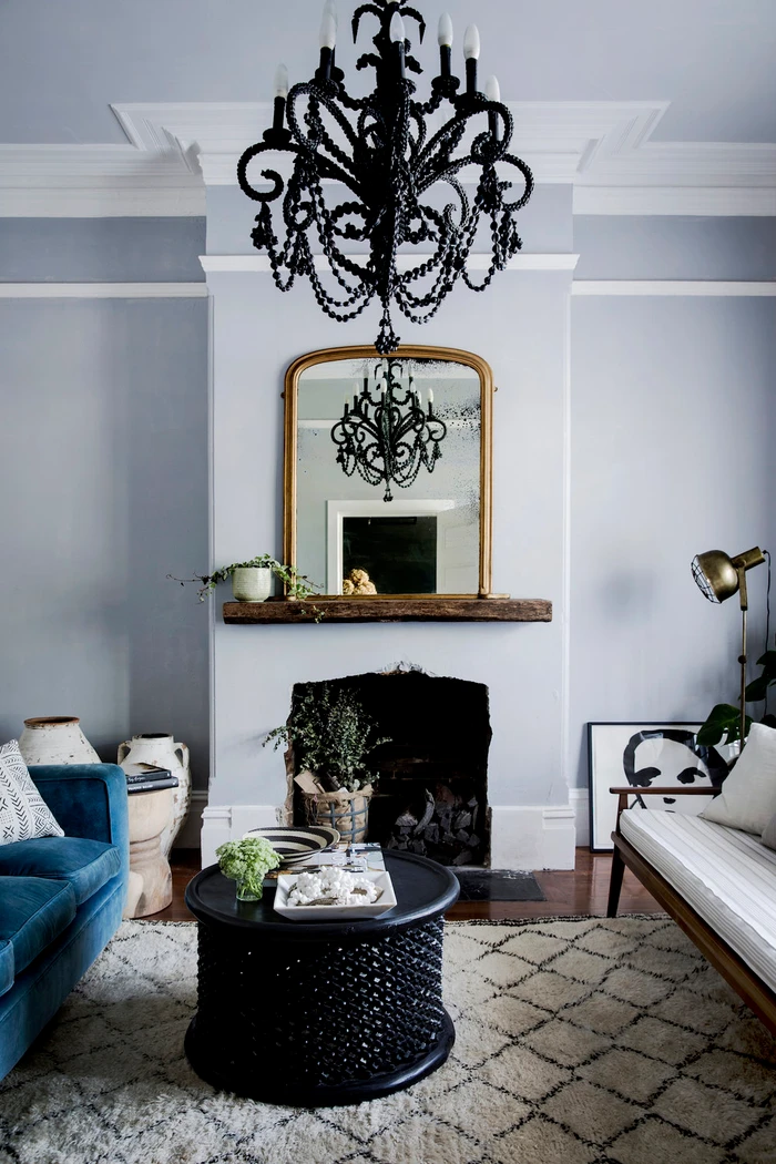 Interior view of a living room styled by Natalie Walton featuring a black beaded chandelier and fireplace mantel with gold mirror