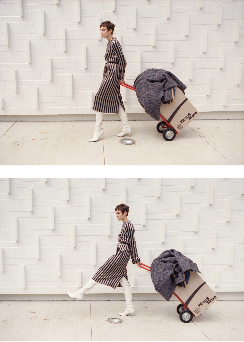 A woman in a striped dress and white boots walks alongside a hand truck loaded with boxes against a textured white wall.