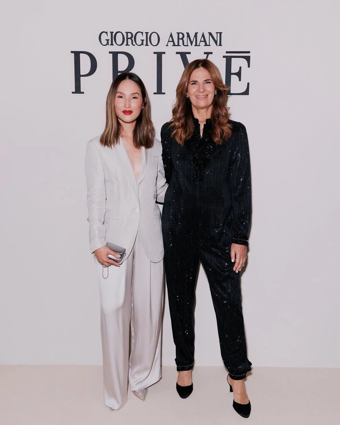 Two women standing side by side in front of a Giorgio Armani Privé backdrop in Sydney