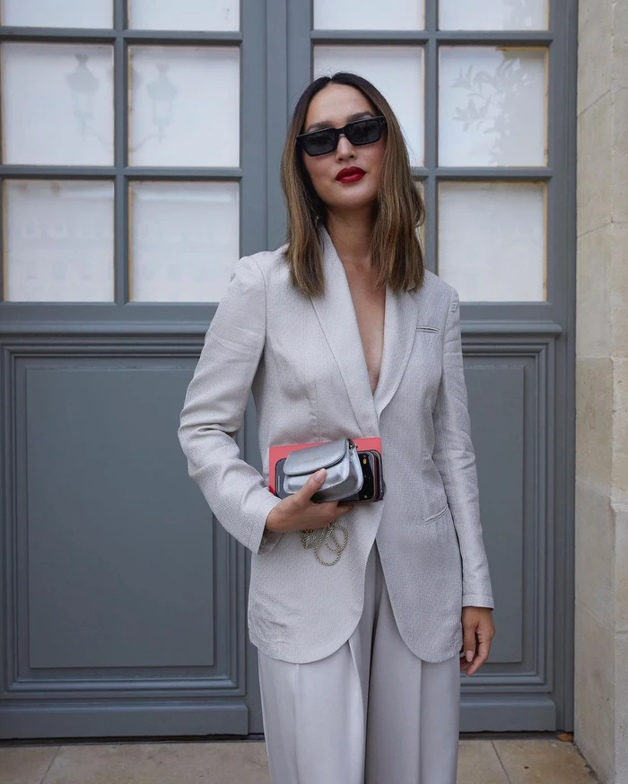Nicole Warne wearing a light grey suit jacket and sunglasses while holding a metallic silver mini bag in Sydney