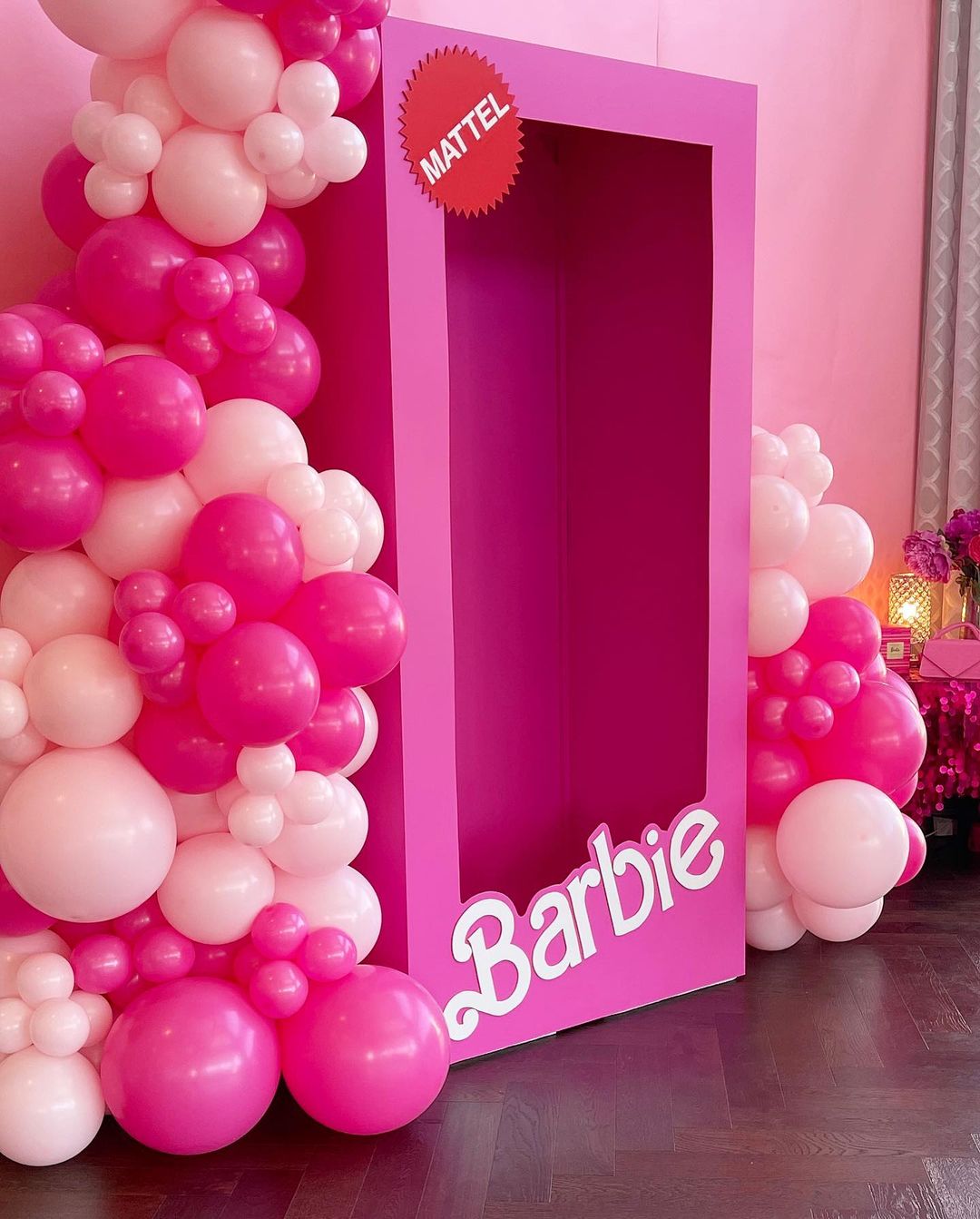 Pink Barbie box surrounded by pink and white balloon garland creating a photo booth backdrop for parties and events.