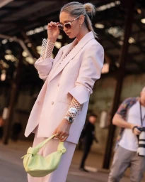 Woman in pink suit wearing cat-eye sunglasses holding a pale yellow handbag in Sydney by Nikki Phillips