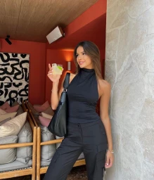 Woman in a black halter top holding a cocktail glass with a black handbag in Sydney