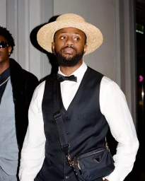 Black man wearing a straw boater hat, white shirt, black vest, bow tie, and crossbody bag in Sydney by Onyedika Agbarakwe