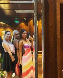 Three women posing in a mirror reflection inside a warmly lit wood-paneled interior in Sydney by content creator Paula Joye.