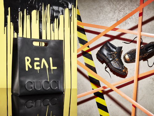 Black Gucci tote bag with painted text beside studded leather boots with orange and black hazard tape on a contrasting surface.