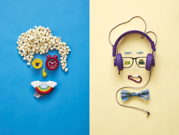 Creative flat lay of two faces constructed from everyday objects on a split blue and yellow background, whimsical, playful, and colorful.