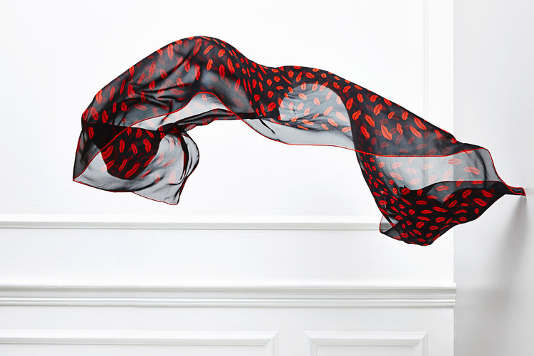 Floating black chiffon fabric with a red lip pattern against a white wall, creating a sense of movement and artistic expression.