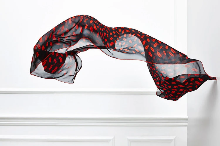 Floating black chiffon fabric with a red lip pattern against a white wall, creating a sense of movement and artistic expression.