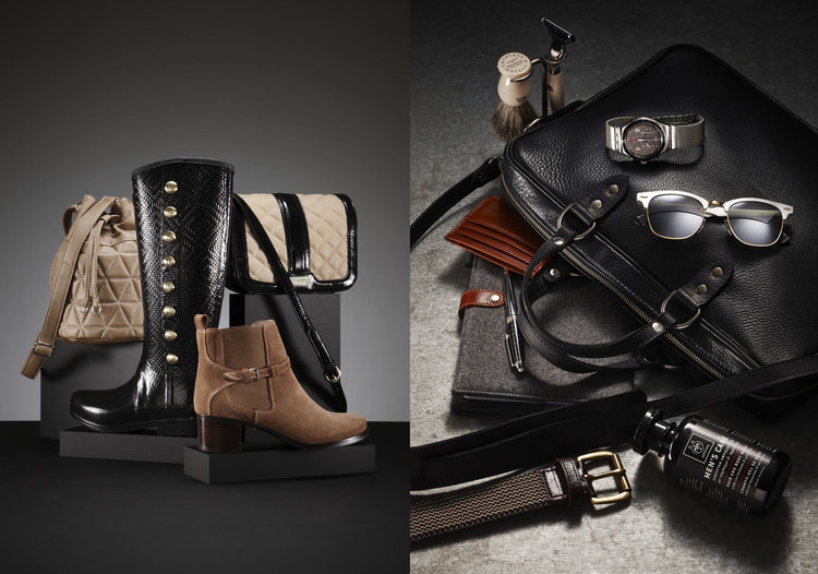 Still life shot of women's and men's fashion accessories on a split grey and black background, including boots, bags, and grooming items.
