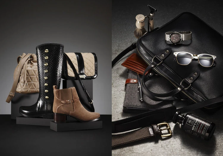 Still life shot of women's and men's fashion accessories on a split grey and black background, including boots, bags, and grooming items.