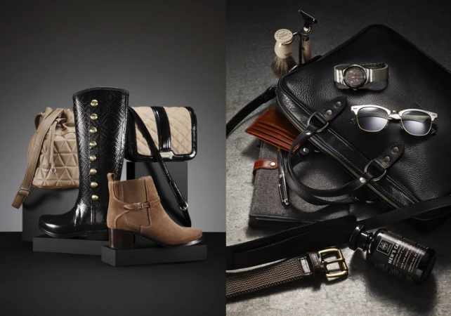 Still life shot of women's and men's fashion accessories on a split grey and black background, including boots, bags, and grooming items.