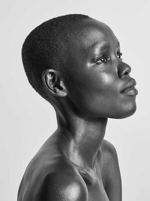 Striking black and white portrait of a sleek, short-haired African woman with a serene expression, gazing elegantly to the right, set against a plain background.