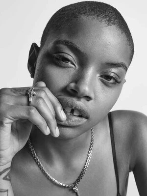 Monochrome portrait of a black woman with a buzzcut wearing a silver chain necklace and ring against a plain background