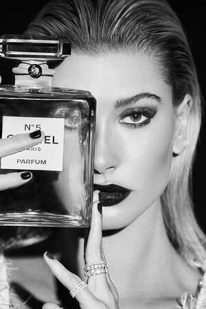 Black and white beauty shot of a woman with dark lipstick and a Chanel No. 5 perfume bottle, showcasing elegance and classic beauty.