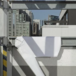 A crisp white shirt draped over an industrial metal railing against an urban skyline backdrop.