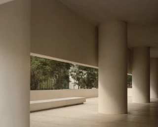 Modern architectural interior with large cylindrical concrete columns framing a view of green trees outside
