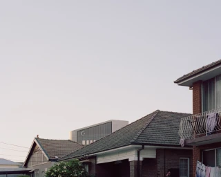 Exterior view of brick residential buildings and a modern architectural structure under a clear sky by Rory Gardiner
