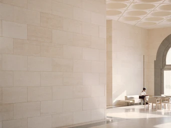Interior architectural view featuring a large stone tile wall with a seated figure in a brightly lit hall by Rory Gardiner