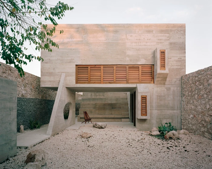 Modern concrete building exterior with wooden window louvers and gravel courtyard photographed by Rory Gardiner