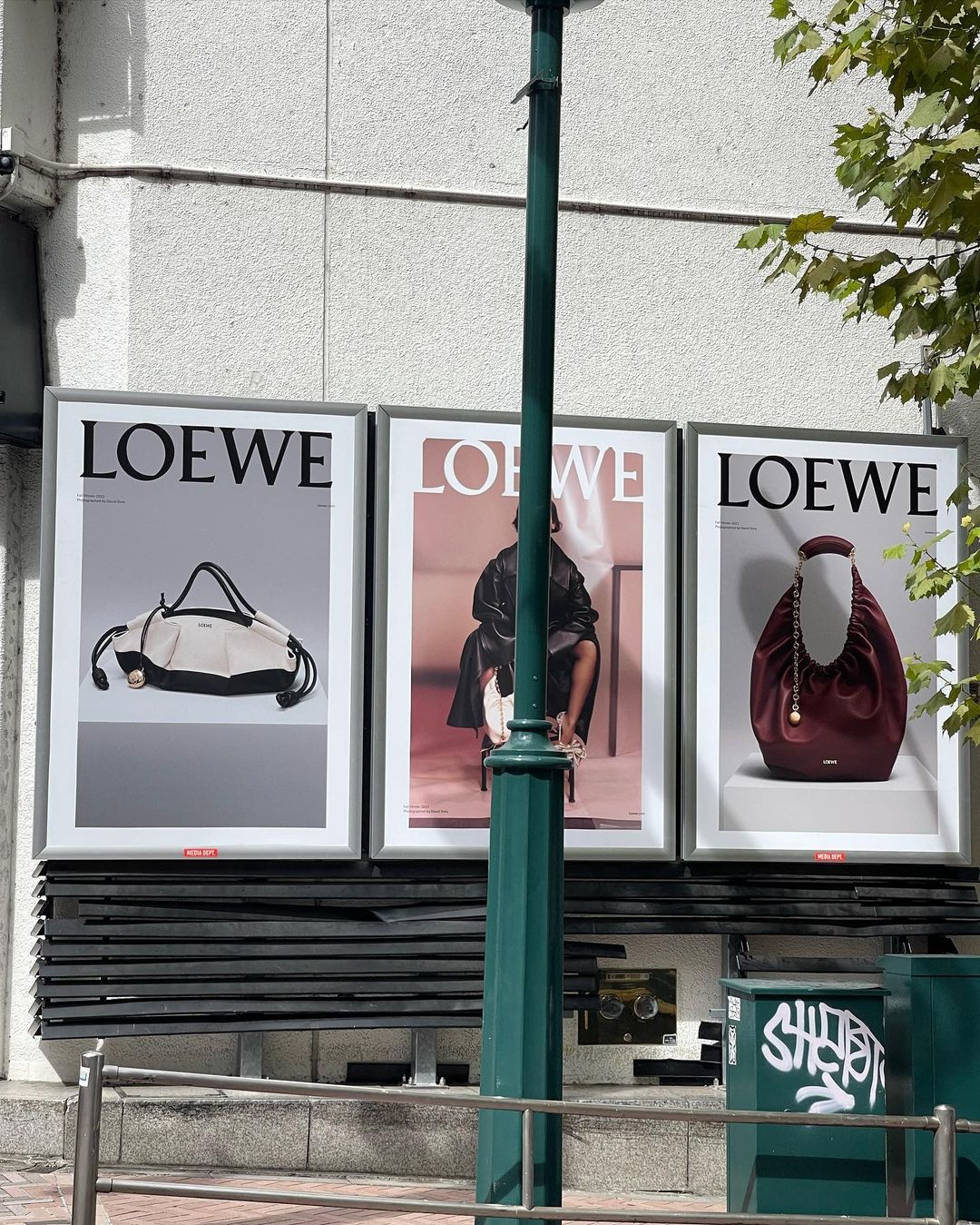 Outdoor ad campaign featuring Loewe handbags on posters mounted to a building, showcasing luxury fashion in an urban setting.