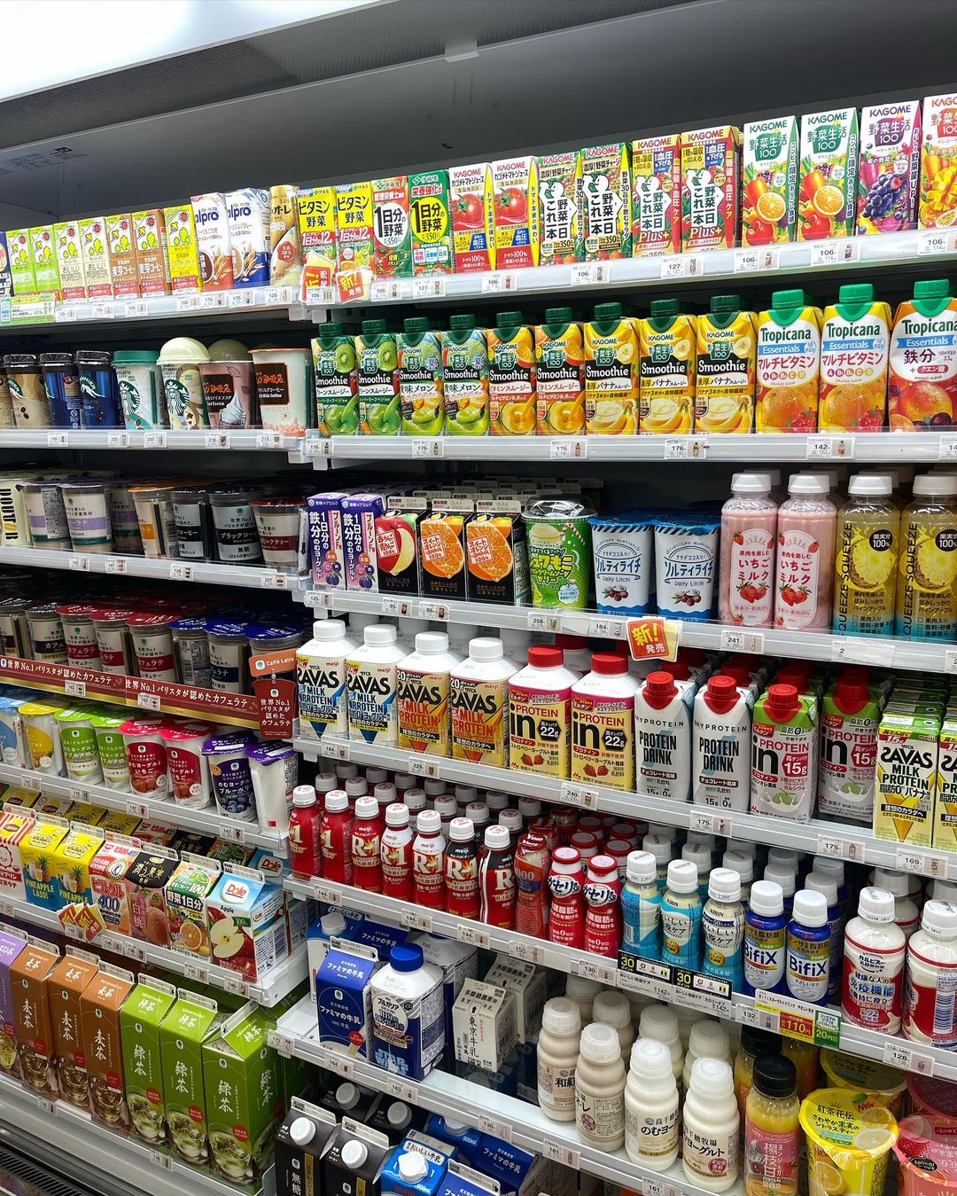 Grocery store shelf stocked with various juice and beverage products in bottles and cartons, showcasing a variety of drinks.
