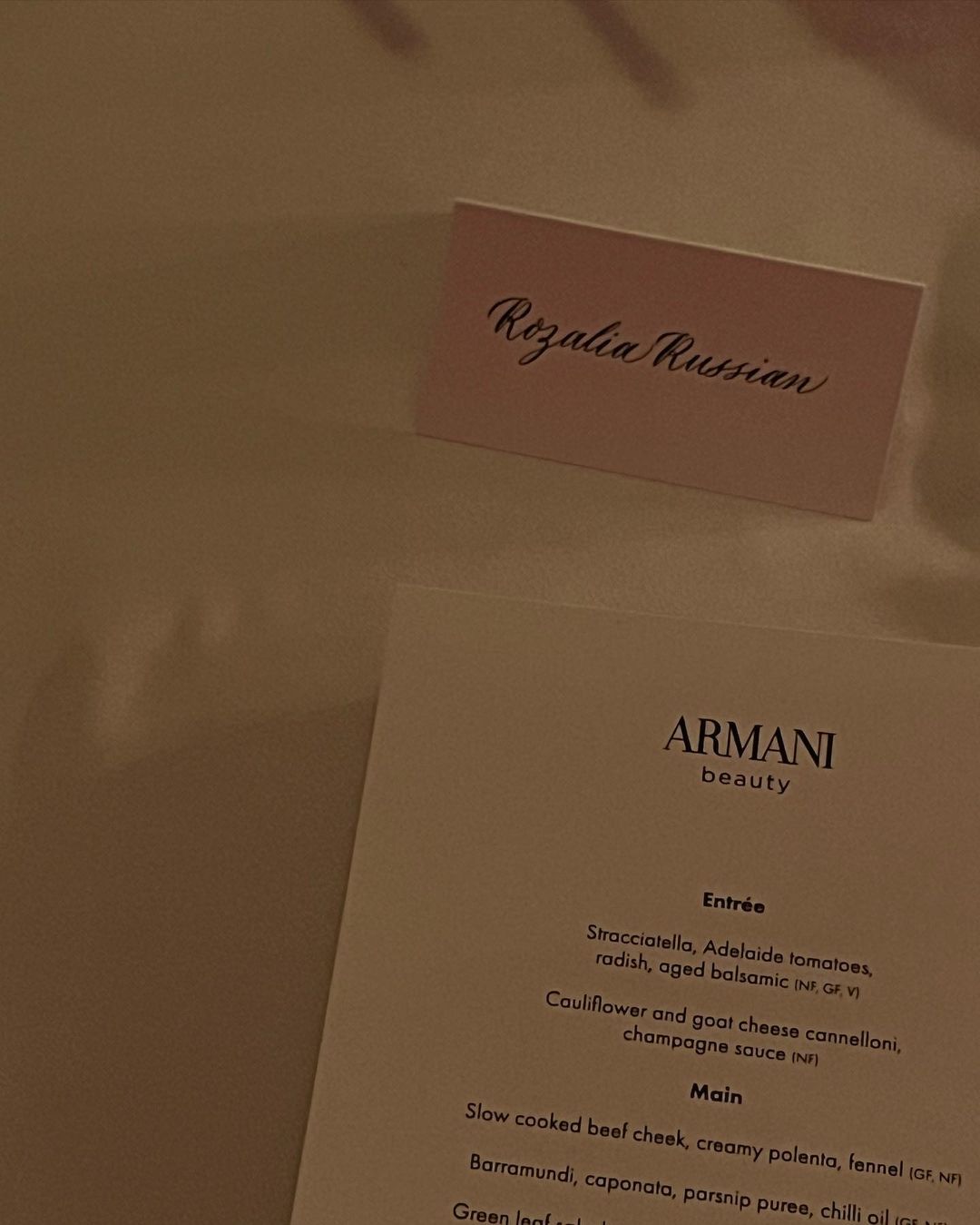 Table setting featuring a name card reading 'Rozalia Russian' and an Armani Beauty menu showcasing upcoming culinary offerings.