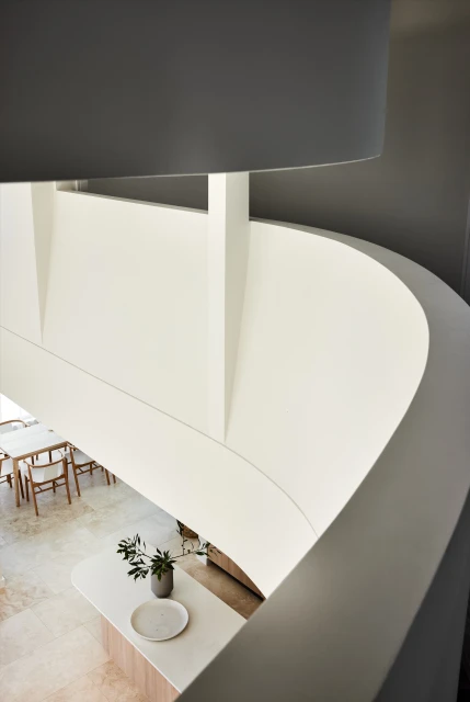 Interior design showcasing a modern home interior with curved walls, staircase, dining area, and minimalist decor, captured from a high angle.