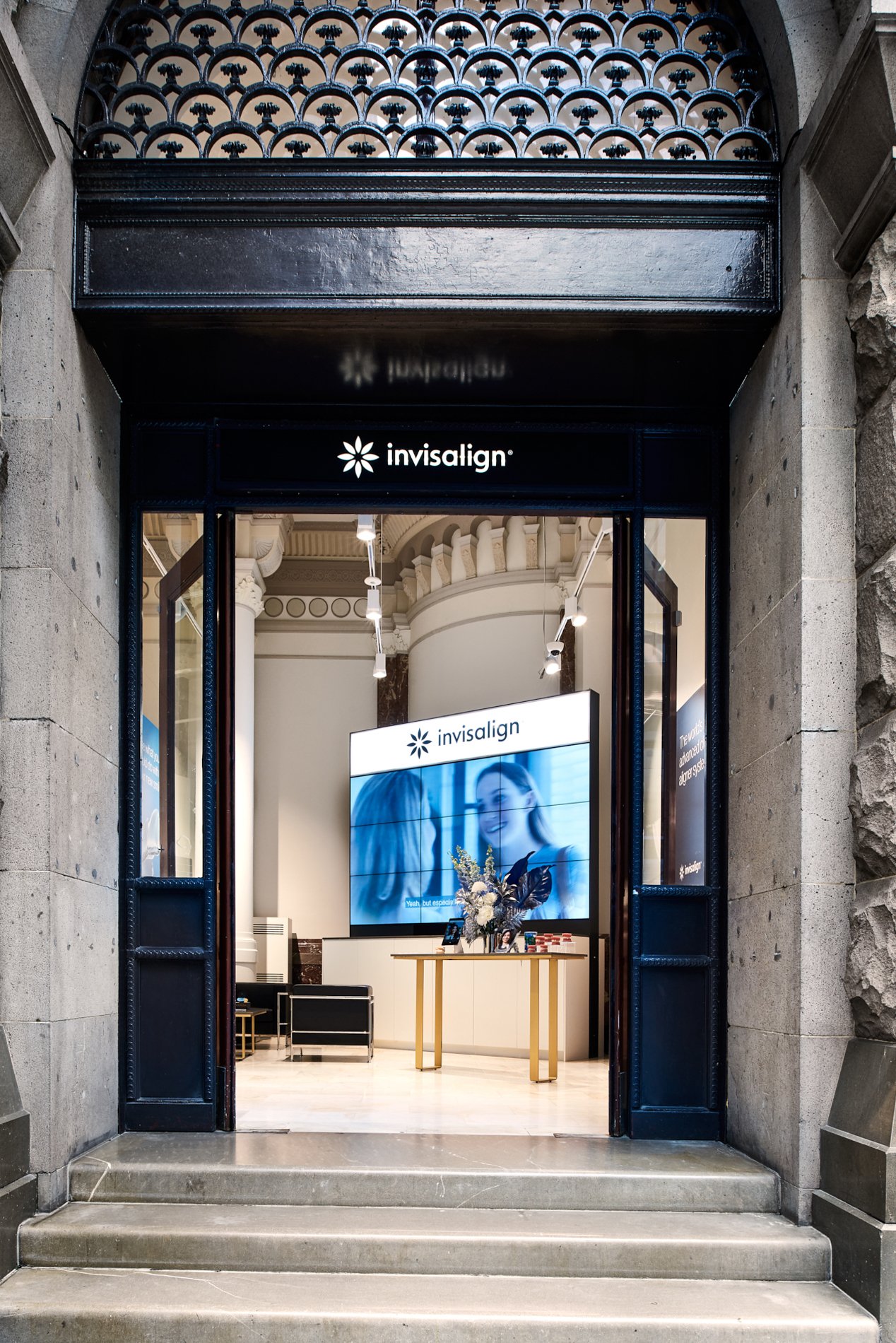 Entrance to a dental clinic, showcasing the Invisalign brand; open door with a display screen and treatment area visible inside.