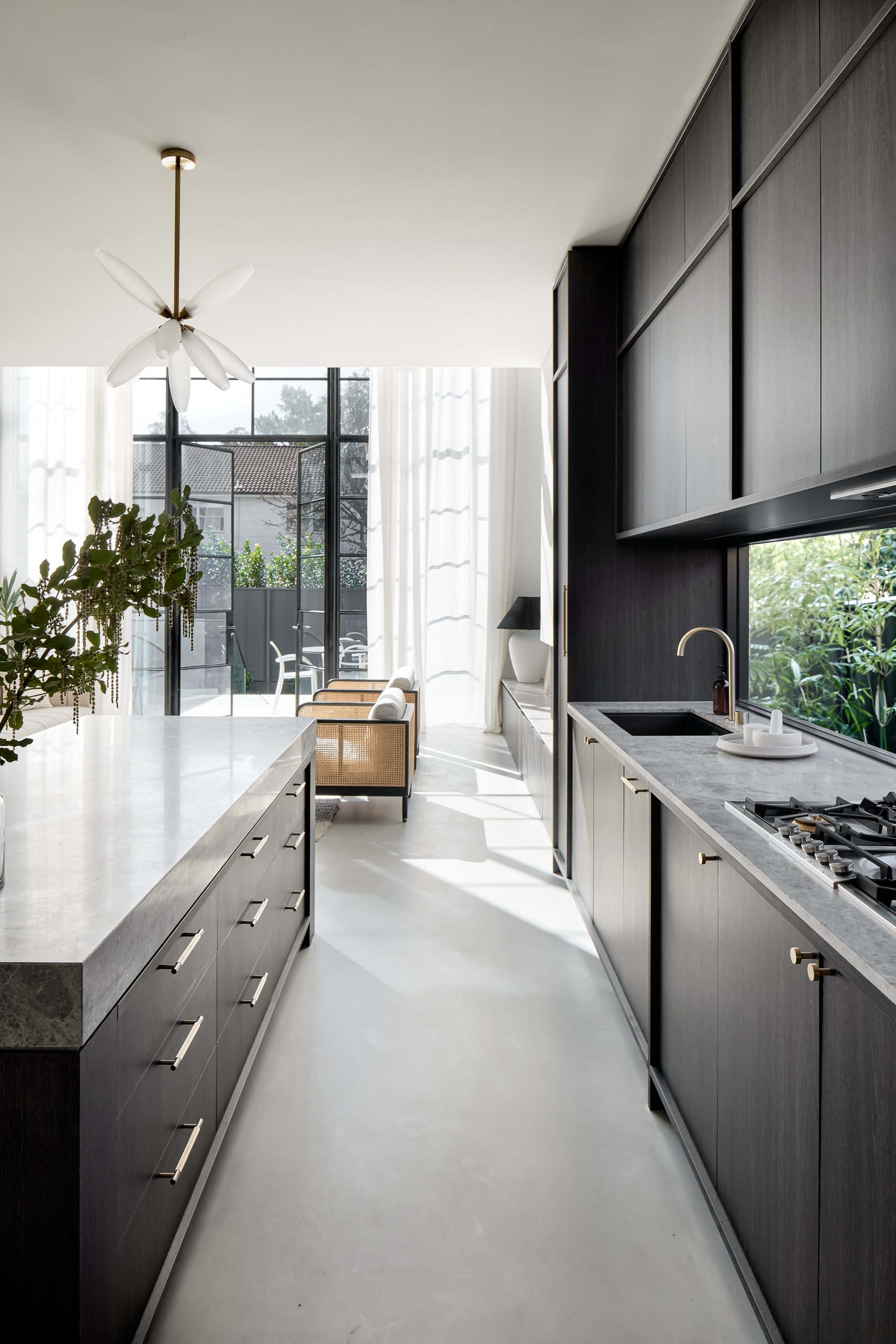 Bright, modern kitchen design featuring dark wood cabinetry, marble countertops, and an open floor plan with natural light from large windows.