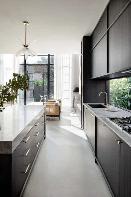 Bright, modern kitchen design featuring dark wood cabinetry, marble countertops, and an open floor plan with natural light from large windows.