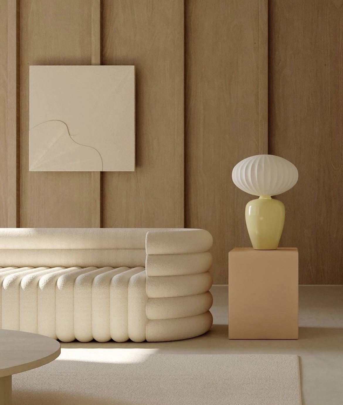 Interior design featuring a cream-colored fluted sofa with a round side table, against a beige wall with a cream-colored lamp.