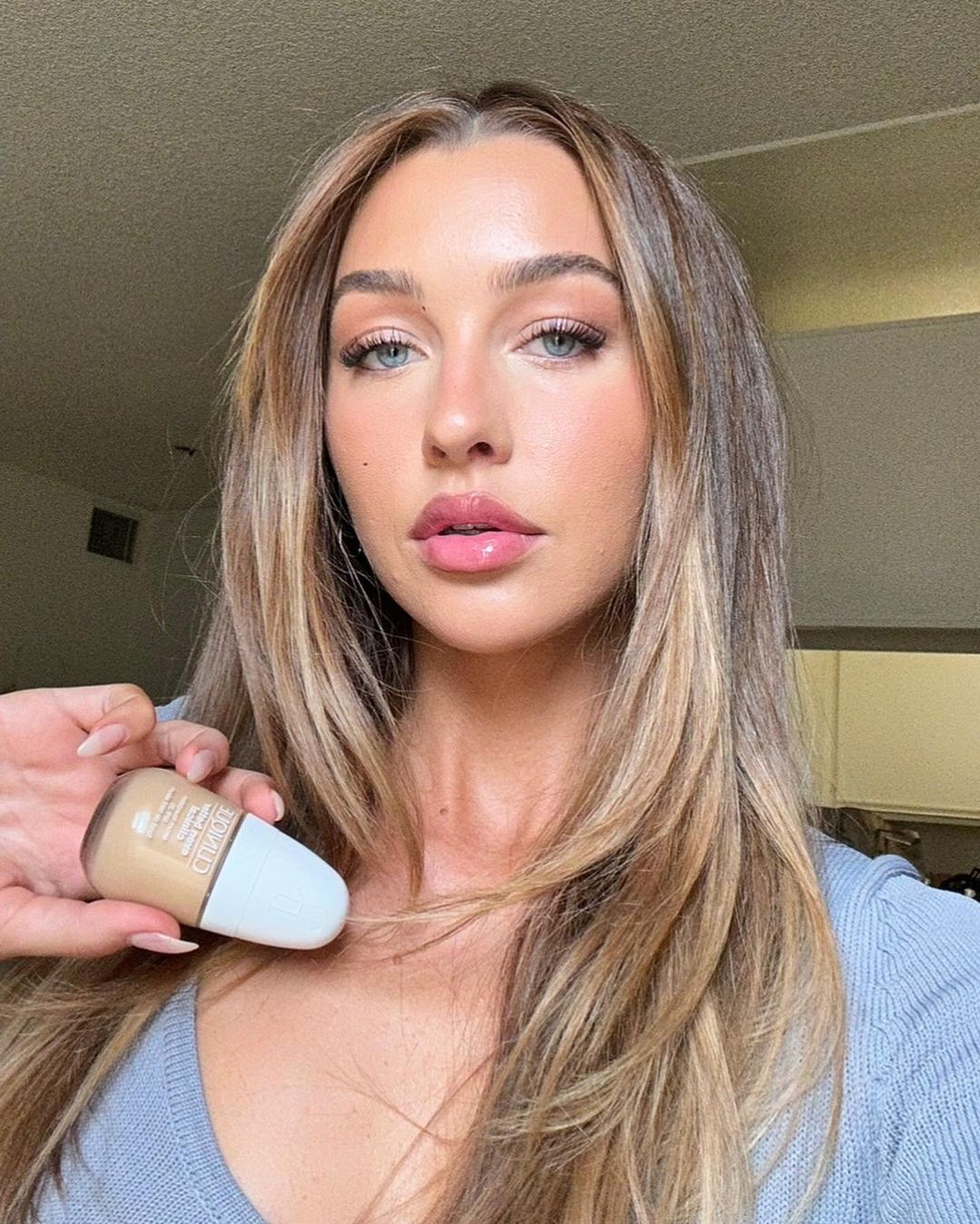 Attractive brunette woman holding Clinique foundation. Portrait shot of skincare and beauty product for cosmetics promotion.