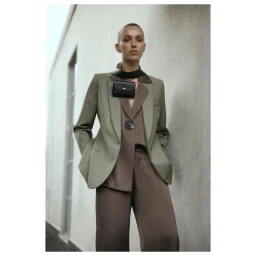 Model wearing an olive green blazer over brown silk trousers with a black crossbody pouch in Sydney
