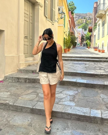 Woman in black halter top and light beige shorts walking down stone steps on a European street
