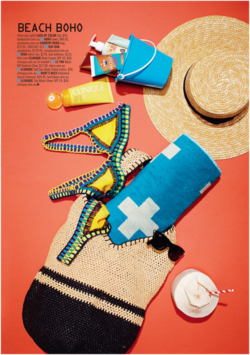 Flat lay of beach and summer vacation accessories including a straw hat, towel, swimsuit, sunblock, sunglasses, and a beach bag.