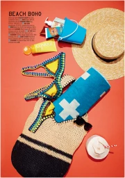 Flat lay of beach accessories on red background including straw hat, blue towel, crochet bikini, and toiletries