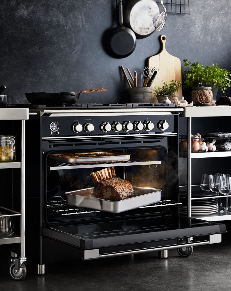 An oven with a roasting rack inside, showcasing a cooked roast, set in a kitchen with cooking utensils and tableware.