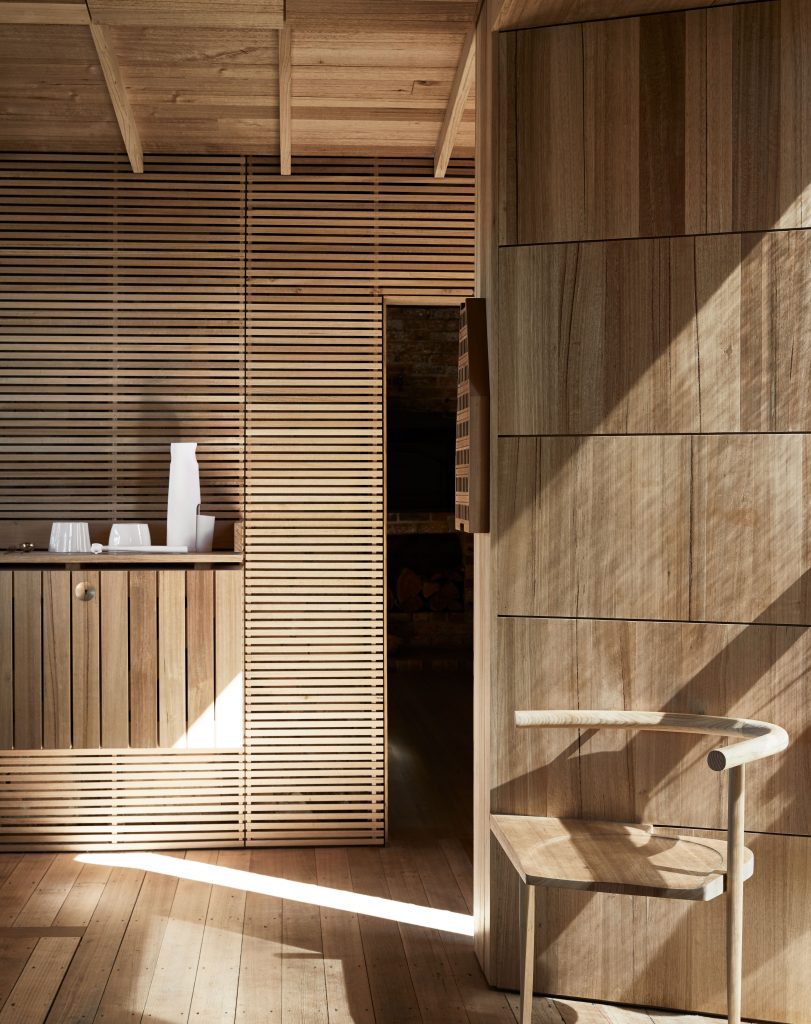 Interior design with wooden walls and floors, featuring modern furniture and architectural details bathed in natural light.