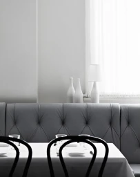 Interior shot featuring a tufted grey banquette booth, white draped table, and black bentwood chairs by photographer Sharyn Cairns.