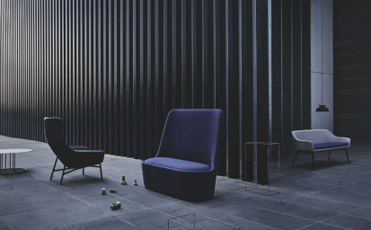 Modern dark blue armchair and matching lounge furniture arranged on a paved patio beneath vertical slat architectural wall panels