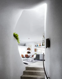 Textured white organic archway framing a view into a modern dining room with chairs, a table, and a skylight.