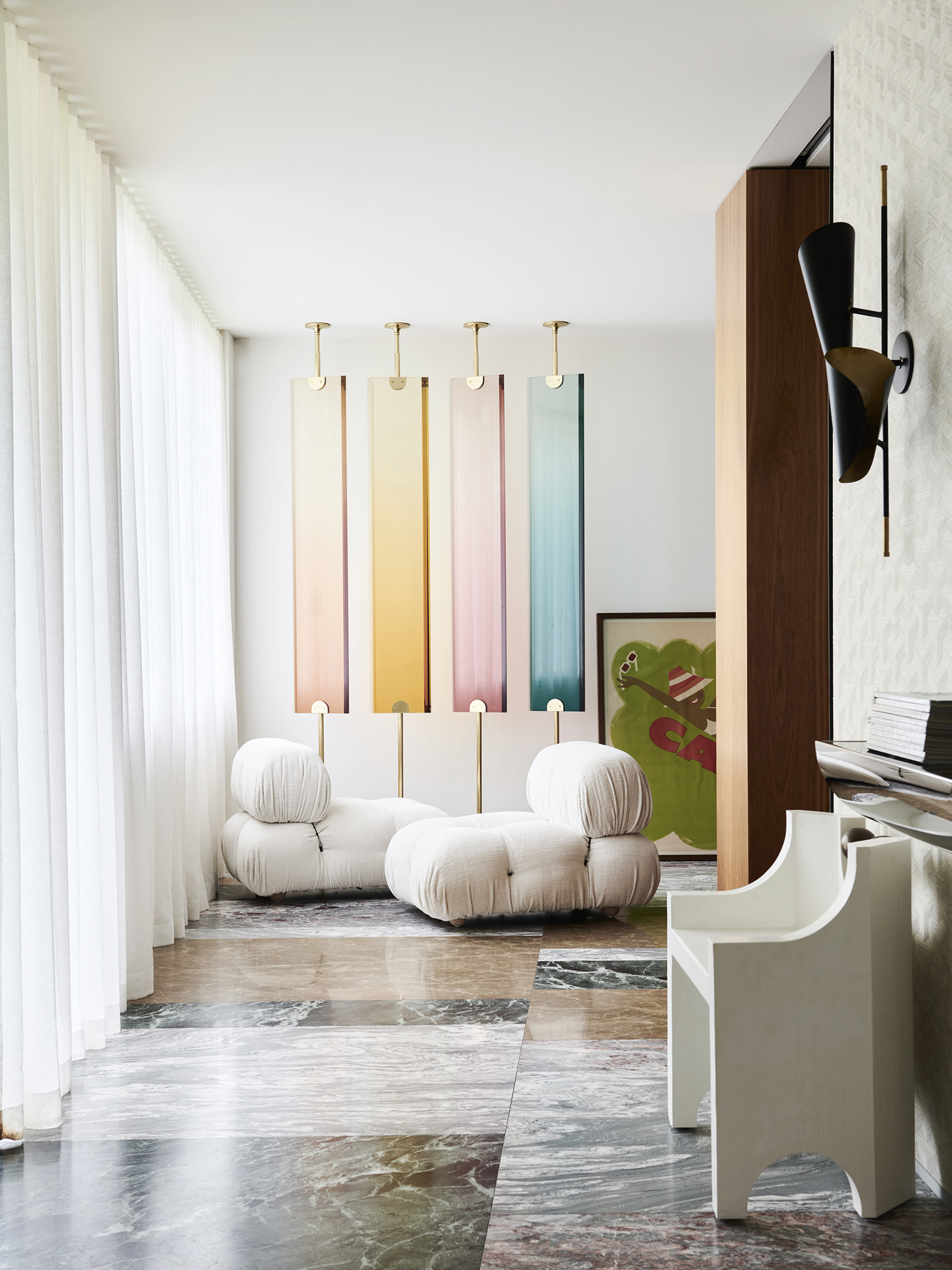Interior view of living room area with two white armchairs, colorful wall panels, and dark marble flooring in a modern architectural design.