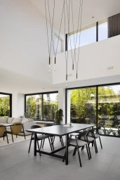 Spacious modern dining room interior styled by Simone Haag with a black table, black chairs, and delicate pendant lights.