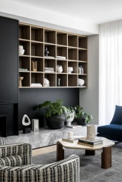 Modern living room interior styled by Simone Haag with wooden grid shelving, marble fireplace hearth, and textured armchairs.