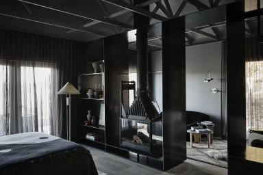 Modern interior styled by Simone Haag featuring a central black fireplace divider and dark built-in shelving in Sydney