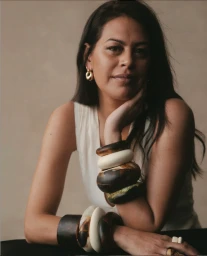 Portrait of a woman wearing chunky resin bangles and gold hoop earrings styled by Katherine Green
