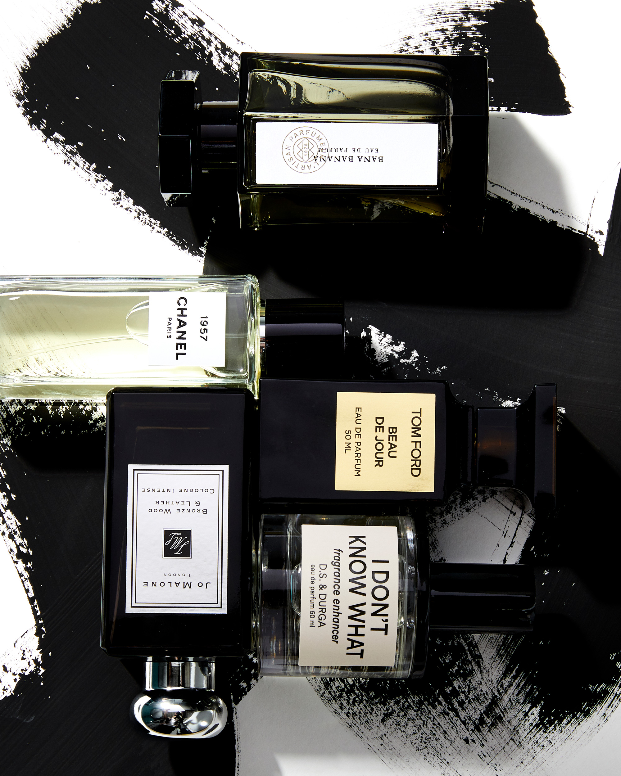 Still life studio shot of perfume bottles including Tom Ford, Chanel, Jo Malone, and DS & Durga on a black and white background.